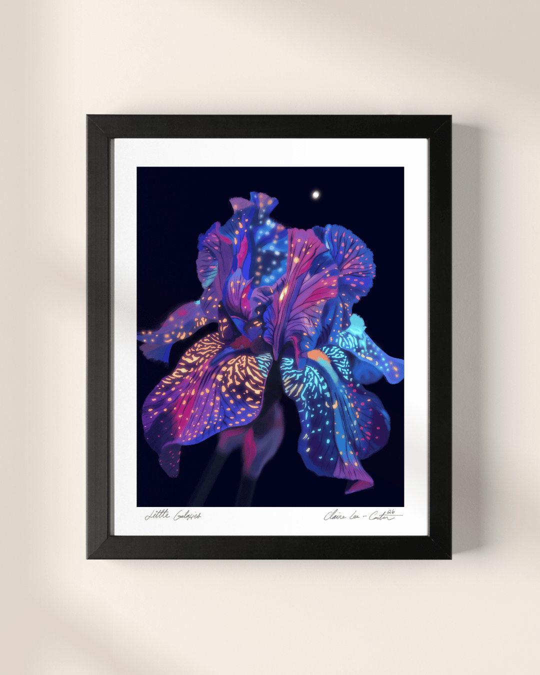 Framed artwork of a rainbow colorful flower that looks galactic like space on a black background with white boarders on a beige wall