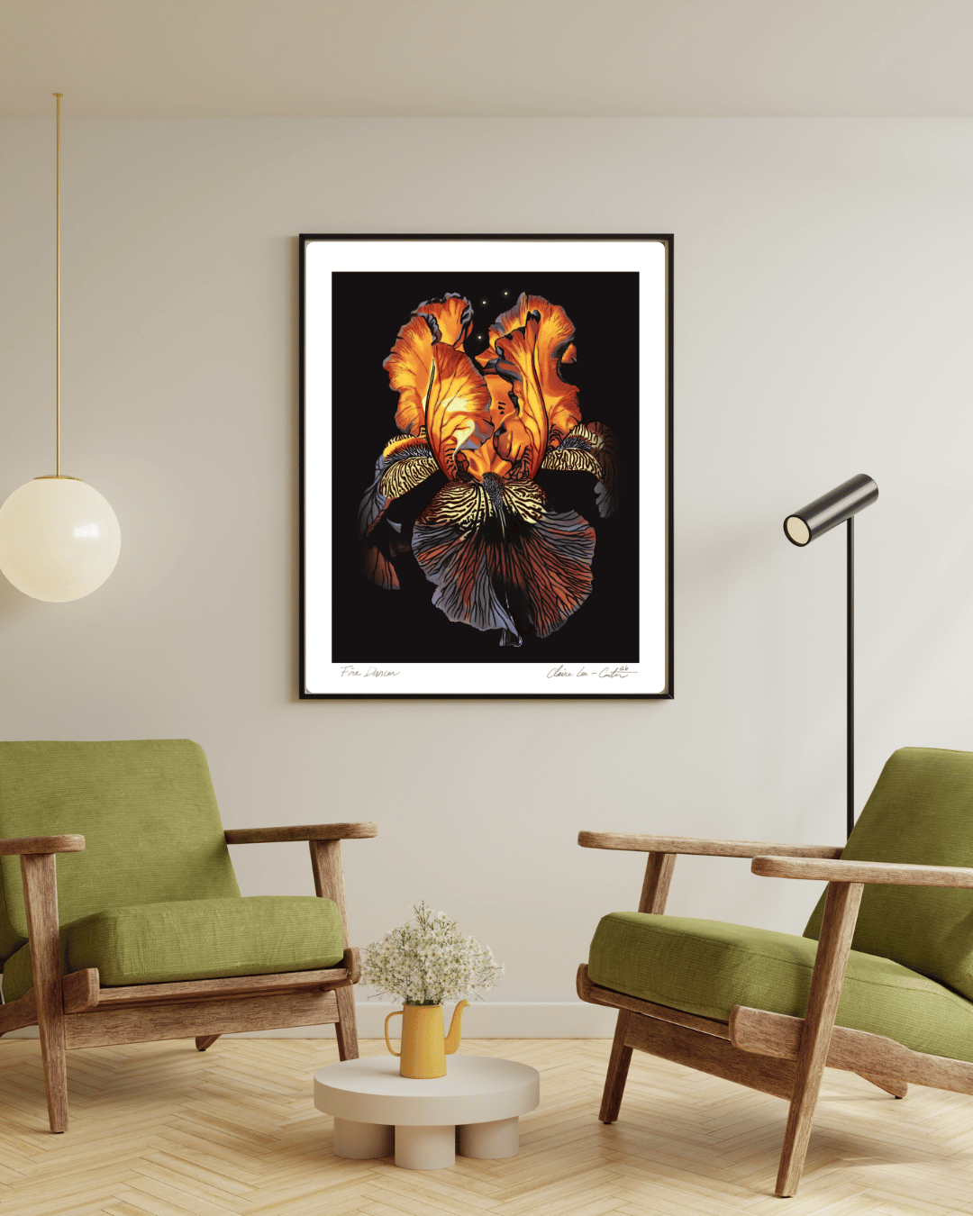 Fine Art Print Framed artwork of a red orange and purple iris flower, that looks like it's glowing from within, on a black background with a white boarder hung on a wall in a modern living room with green chairs and a small table. 