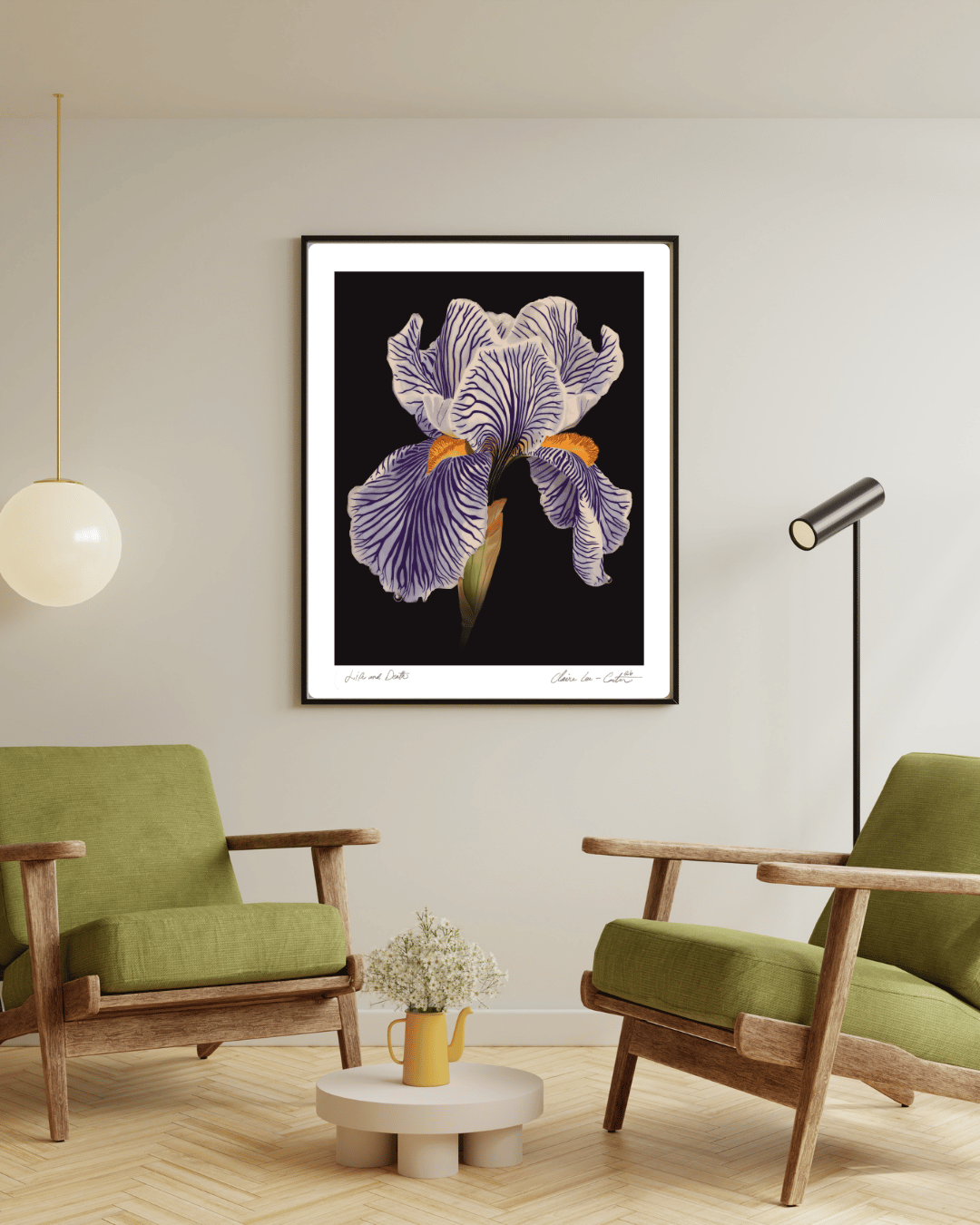 Fine Art Print Framed artwork of a white iris flower on a black background with a white boarder hung on a wall in a room with green chairs and a small table. 